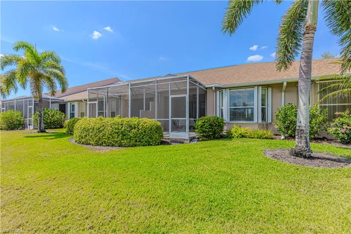 Back of house featuring a yard, a lanai, a sunroom, and stucco siding