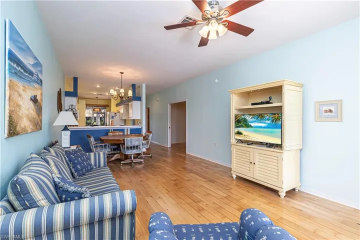 Living room with a chandelier, light wood-style floors, and ceiling fan