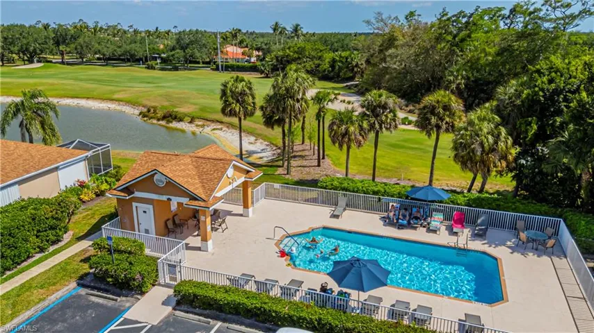 Community pool featuring a patio area, a water view, view of golf course, and view of scattered trees