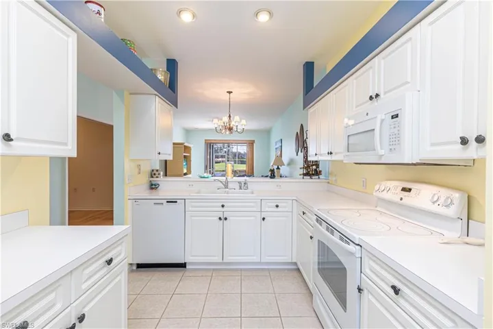 Kitchen with white appliances, light countertops, and white cabinets