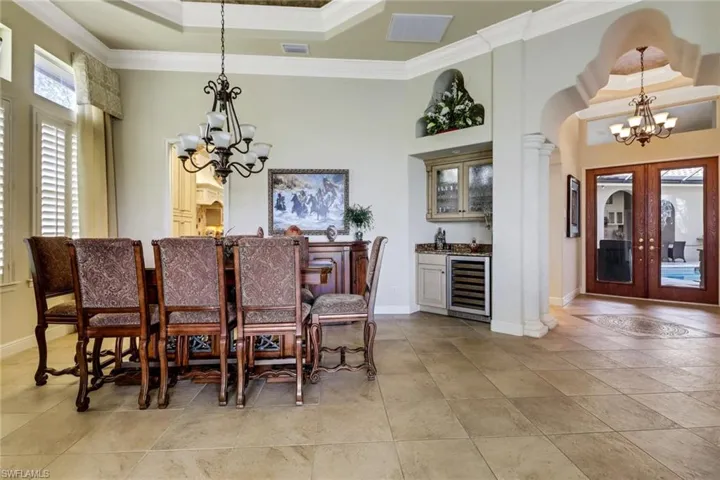 Dining space featuring arched walkways, wet bar, a lovely chandelier, and crown molding
