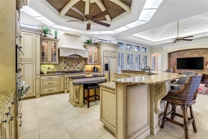 Kitchen with stainless steel appliances, premium range hood, a breakfast bar, a large island, beautiful ceiling inlays, and large pantry.
