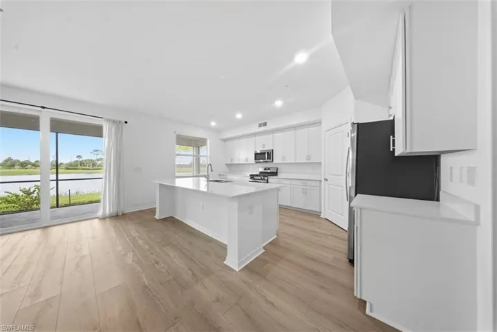 Kitchen featuring white cabinetry, a center island with sink, recessed lighting, appliances with stainless steel finishes, and light wood-style flooring