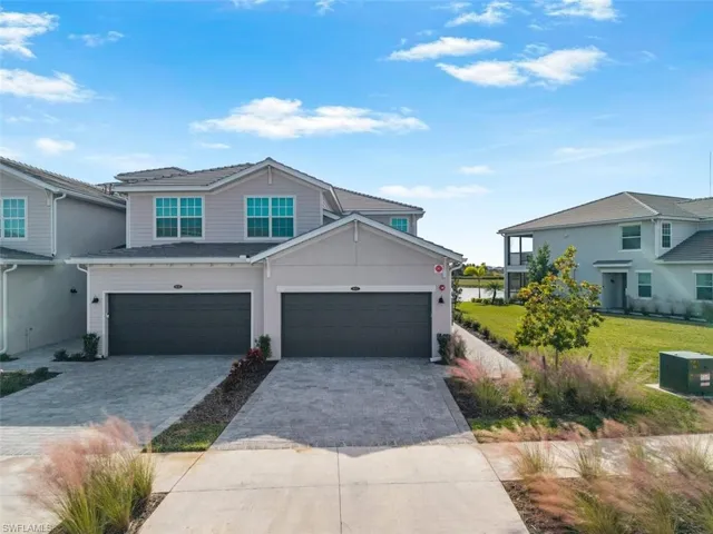 Traditional-style house with decorative driveway, an attached garage, and a front lawn