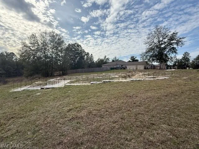 View of yard with fence and a rural view