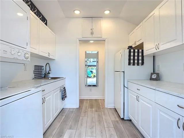 Kitchen with white cabinetry, light wood-type flooring, freestanding refrigerator, lofted ceiling, and recessed lighting