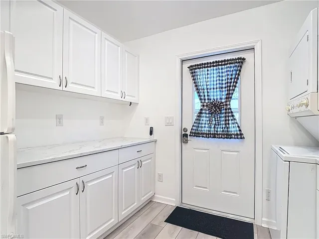 Washroom with stacked washer and clothes dryer and wood tiled floors