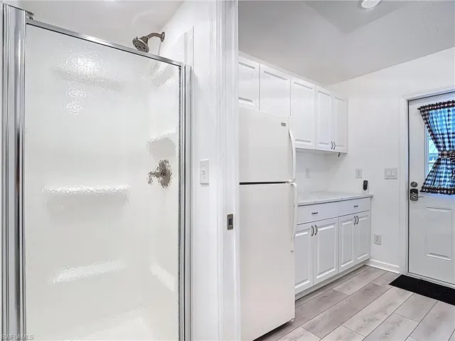 Kitchen featuring white cabinetry, freestanding refrigerator, light countertops, and wood tiled floors