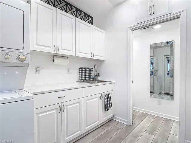 Laundry area featuring wood tiled floors and stacked washer / drying machine