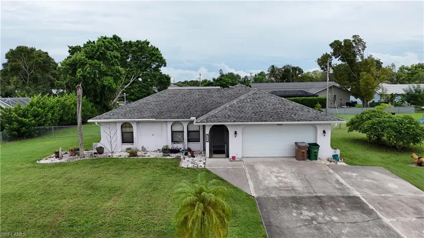 Ranch-style house with driveway, roof with shingles, an attached garage, and stucco siding