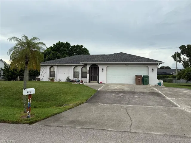 Ranch-style home featuring concrete driveway, a shingled roof, a front lawn, stucco siding, and an attached garage