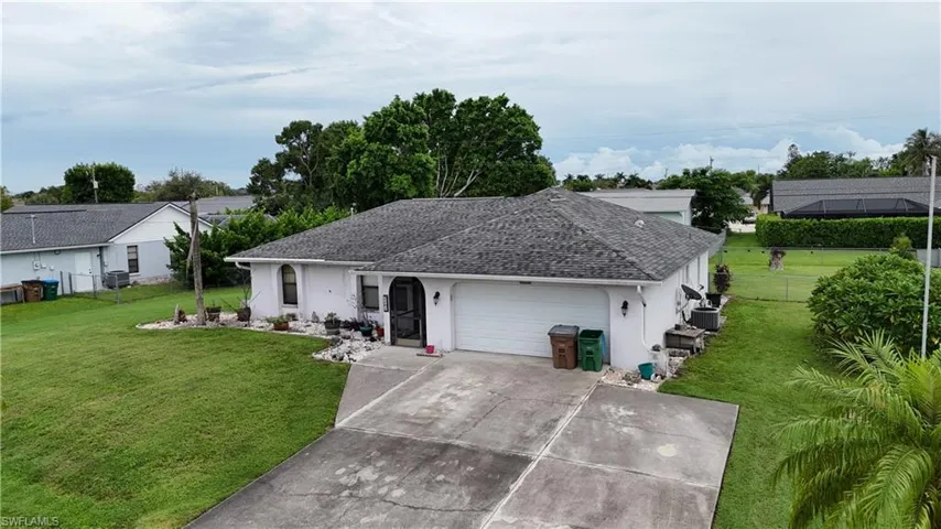 Ranch-style house with stucco siding, roof with shingles, driveway, and a garage