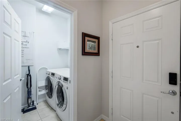 Dedicated laundry area with tiled flooring, featuring a front-loading washer and dryer