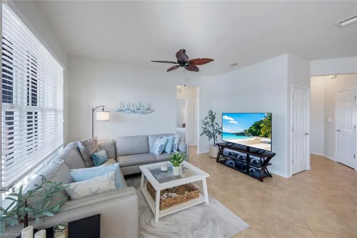 Bright living area featuring light-toned tile flooring and white walls