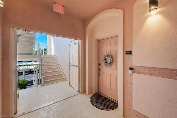 Building entryway featuring a panel door, stucco exterior, and a contemporary wall-mounted light fixture