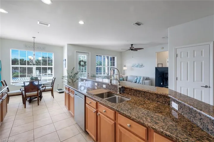 Kitchen with granite countertops, stainless steel sink, and wood cabinetry