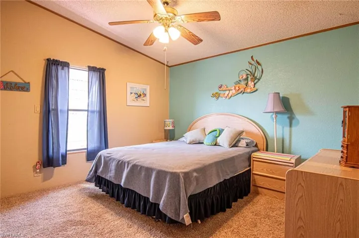 Bedroom with vaulted ceiling, crown molding, carpet floors, and a textured ceiling