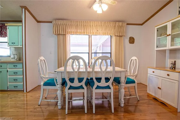 Dining room featuring a ceiling fan, ornamental molding, light wood-style floors, and a textured ceiling