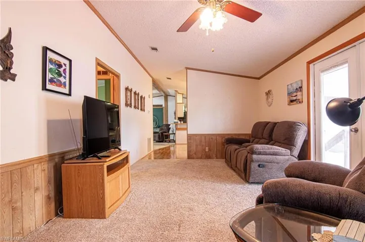 Living area with carpet floors, a textured ceiling, wood walls, and wainscoting