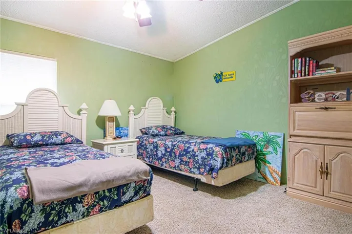 Carpeted bedroom with crown molding, ceiling fan, and a textured ceiling