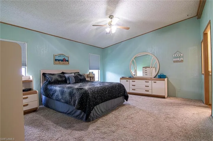 Bedroom with carpet floors, a textured ceiling, ceiling fan, and crown molding