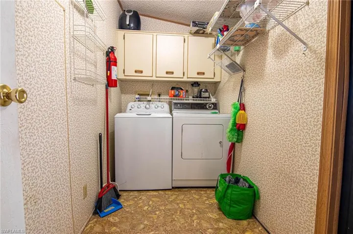 Clothes washing area with cabinet space, separate washer and dryer, and a textured ceiling