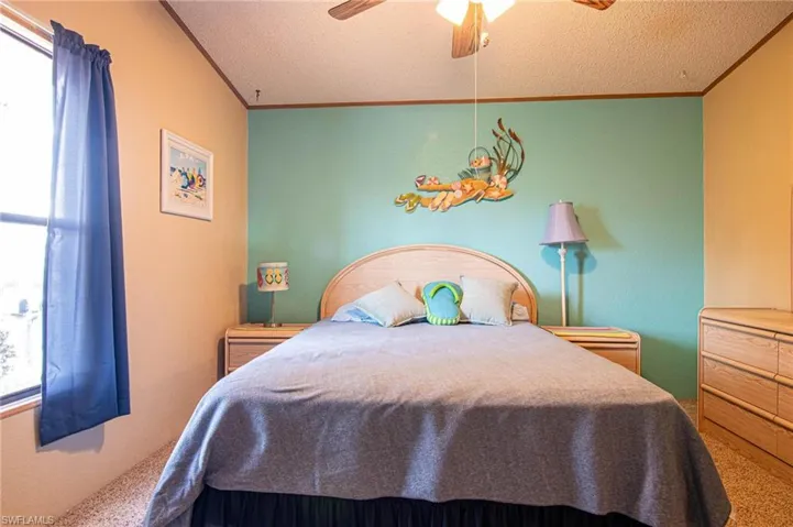 Bedroom featuring a textured ceiling, ceiling fan, and crown molding