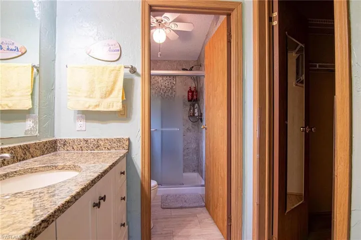 Full bath featuring vanity, a textured wall, toilet, and a shower stall