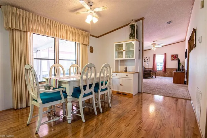 Dining area with a textured ceiling, lofted ceiling, and a ceiling fan