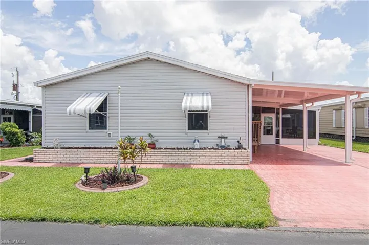 View of front of property with a front lawn, an attached carport, and decorative driveway