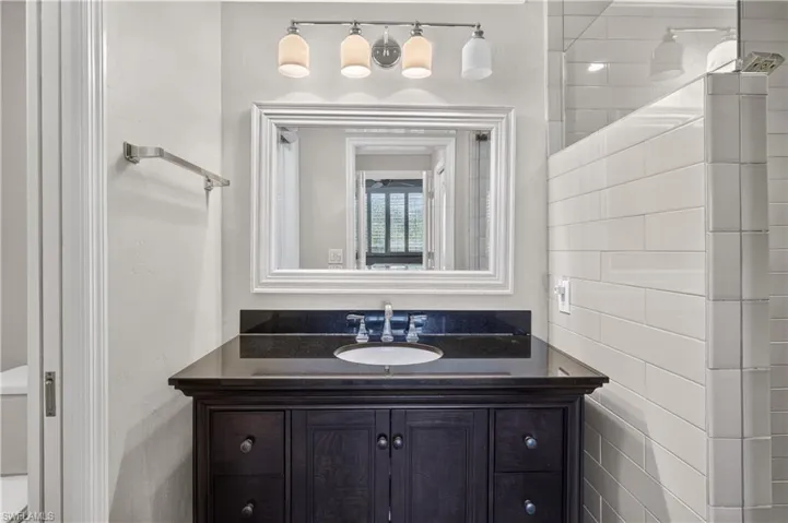 Vanity featuring a dark wood finish, a black countertop, and a white undermount sink