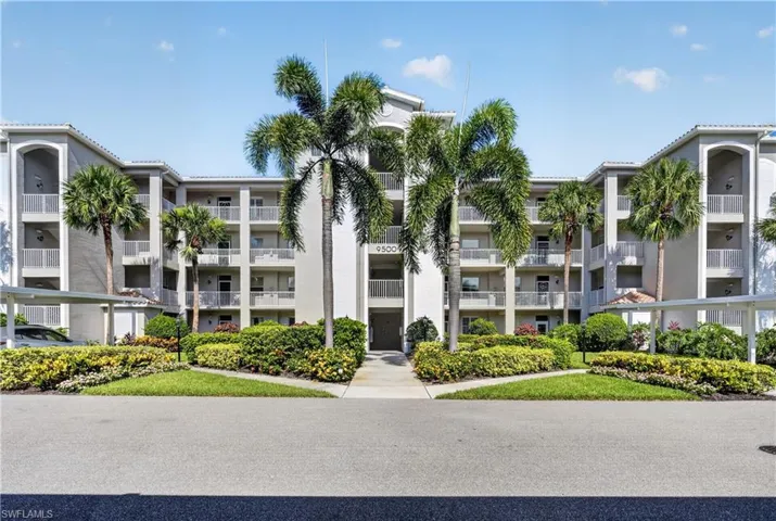 Multi-story residential building with light gray stucco exterior and white railings