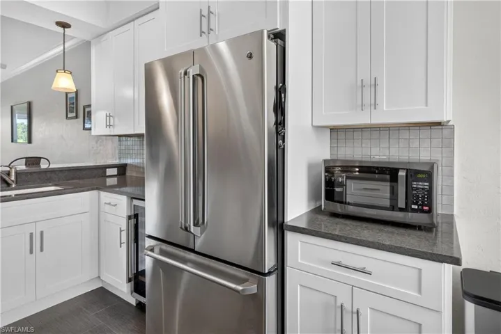 Kitchen featuring white shaker cabinetry, stainless steel French door refrigerator, dark stone countertops, and a subway tile backsplash