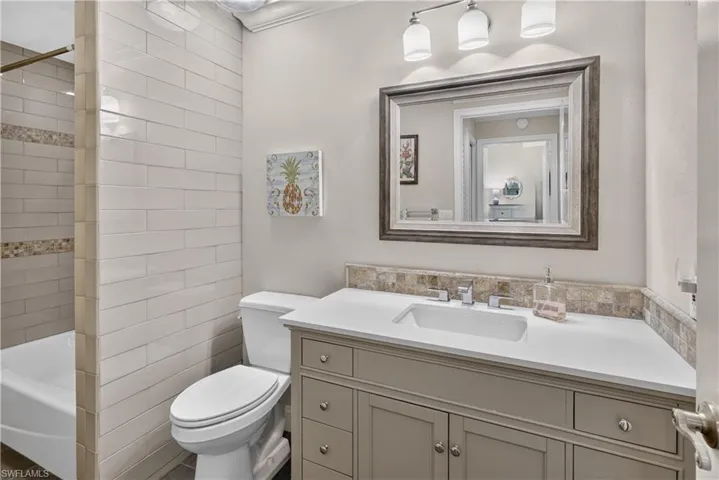 Bathroom featuring a vanity with a white countertop and undermount sink, framed mirror, and a three-light fixture