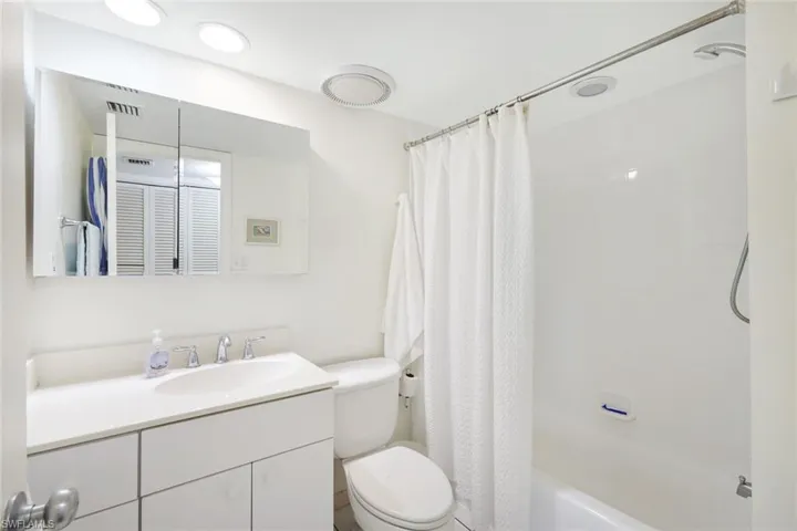 Full bathroom featuring shower / bath combo with shower curtain, vanity, and toilet