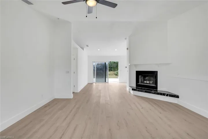 Unfurnished living room featuring ceiling fan, a fireplace, and light hardwood / wood-style flooring