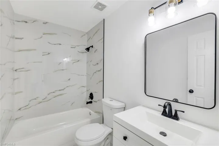 Full bathroom featuring tiled shower / bath combo, vanity, and toilet