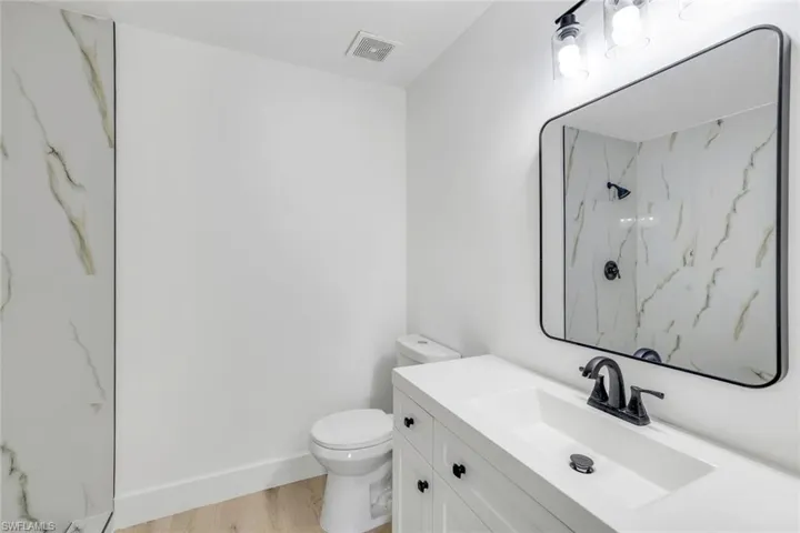 Bathroom featuring vanity, hardwood / wood-style floors, toilet, and a shower