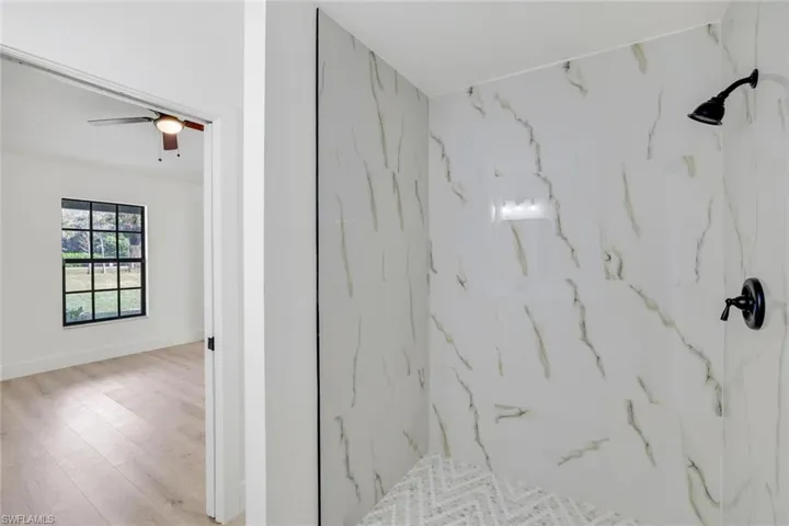 Bathroom featuring ceiling fan, tiled shower, and hardwood / wood-style floors