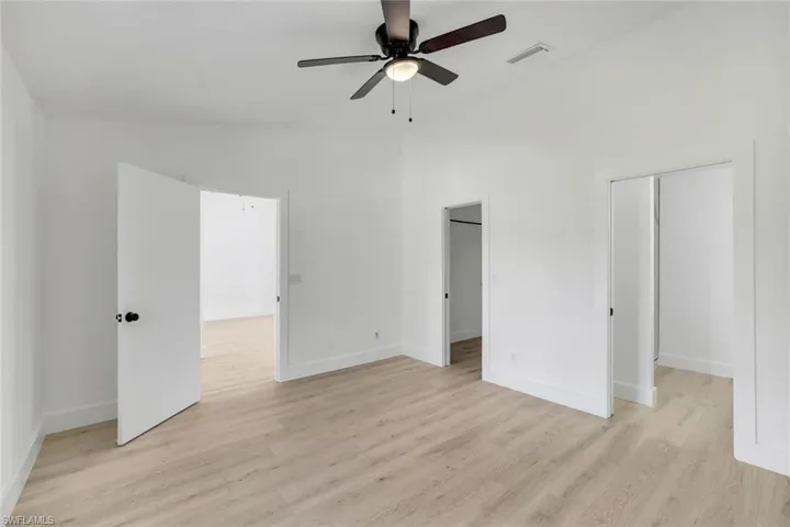 Unfurnished bedroom featuring ceiling fan, vaulted ceiling, and light hardwood / wood-style flooring