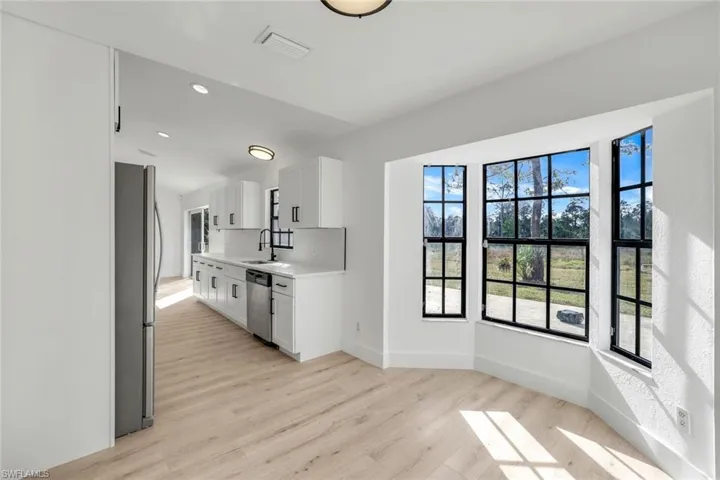 Kitchen with white cabinetry, appliances with stainless steel finishes, sink, and light wood-type flooring