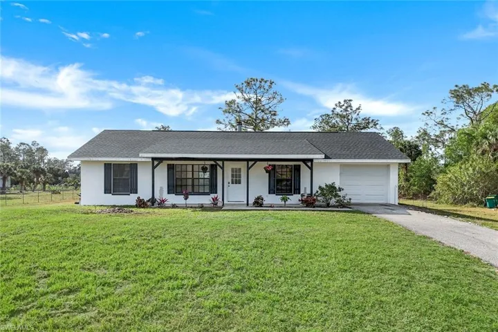 Ranch-style house featuring a garage, a front yard, and a porch
