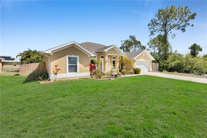 Ranch-style house featuring stucco siding, a front yard, fence, an attached garage, and concrete driveway