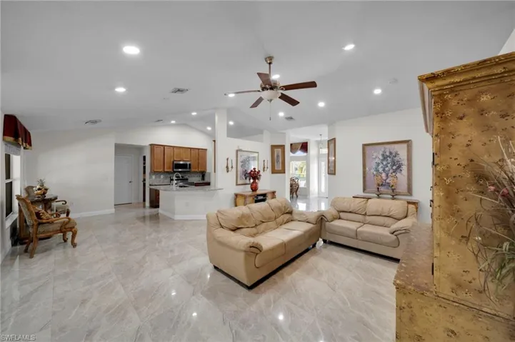 Living area featuring baseboards, vaulted ceiling, visible vents, ceiling fan, and marble finish floor