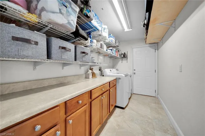 Laundry area featuring washer and dryer, baseboards, and cabinet space