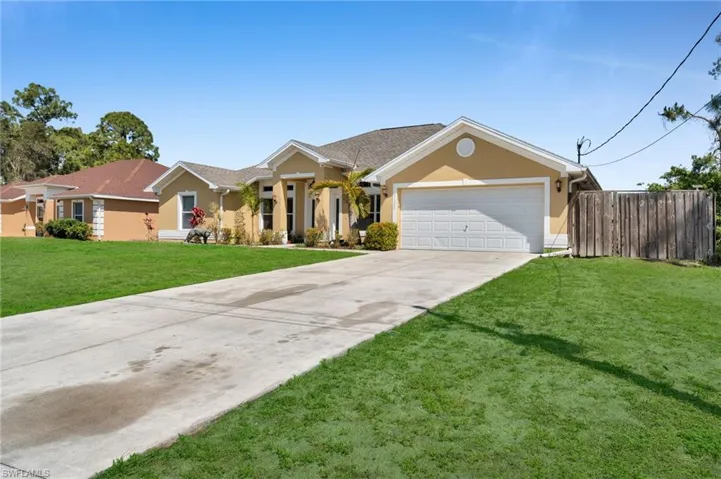 Single story home featuring stucco siding, a front yard, fence, an attached garage, and driveway