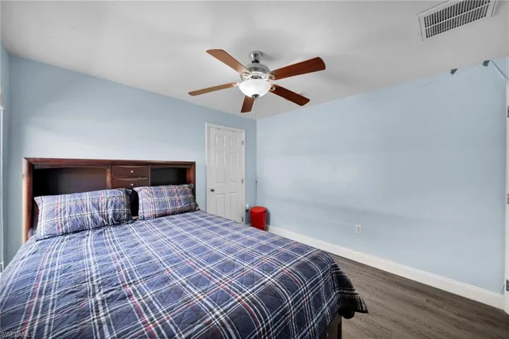 Bedroom featuring visible vents, baseboards, a ceiling fan, and wood finished floors