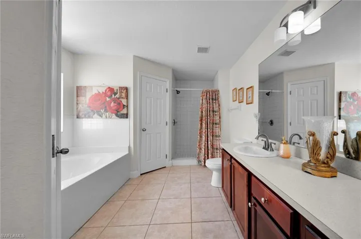 Bathroom featuring tile patterned flooring, visible vents, a tile shower, and toilet