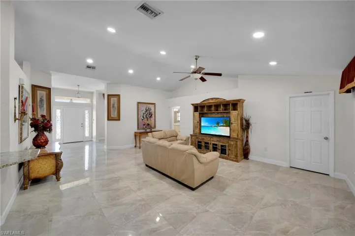Living room featuring visible vents, baseboards, a ceiling fan, and lofted ceiling