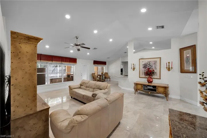 Living room with vaulted ceiling, recessed lighting, a ceiling fan, visible vents, and marble finish floor